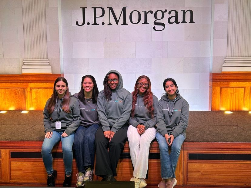 Group five girls sat down on a ledge smiling