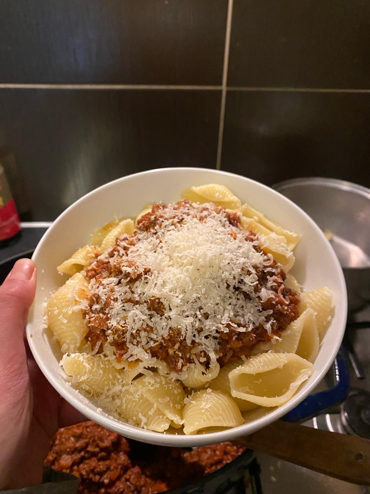 Photo of red wine being poured into a pot of bolognese.