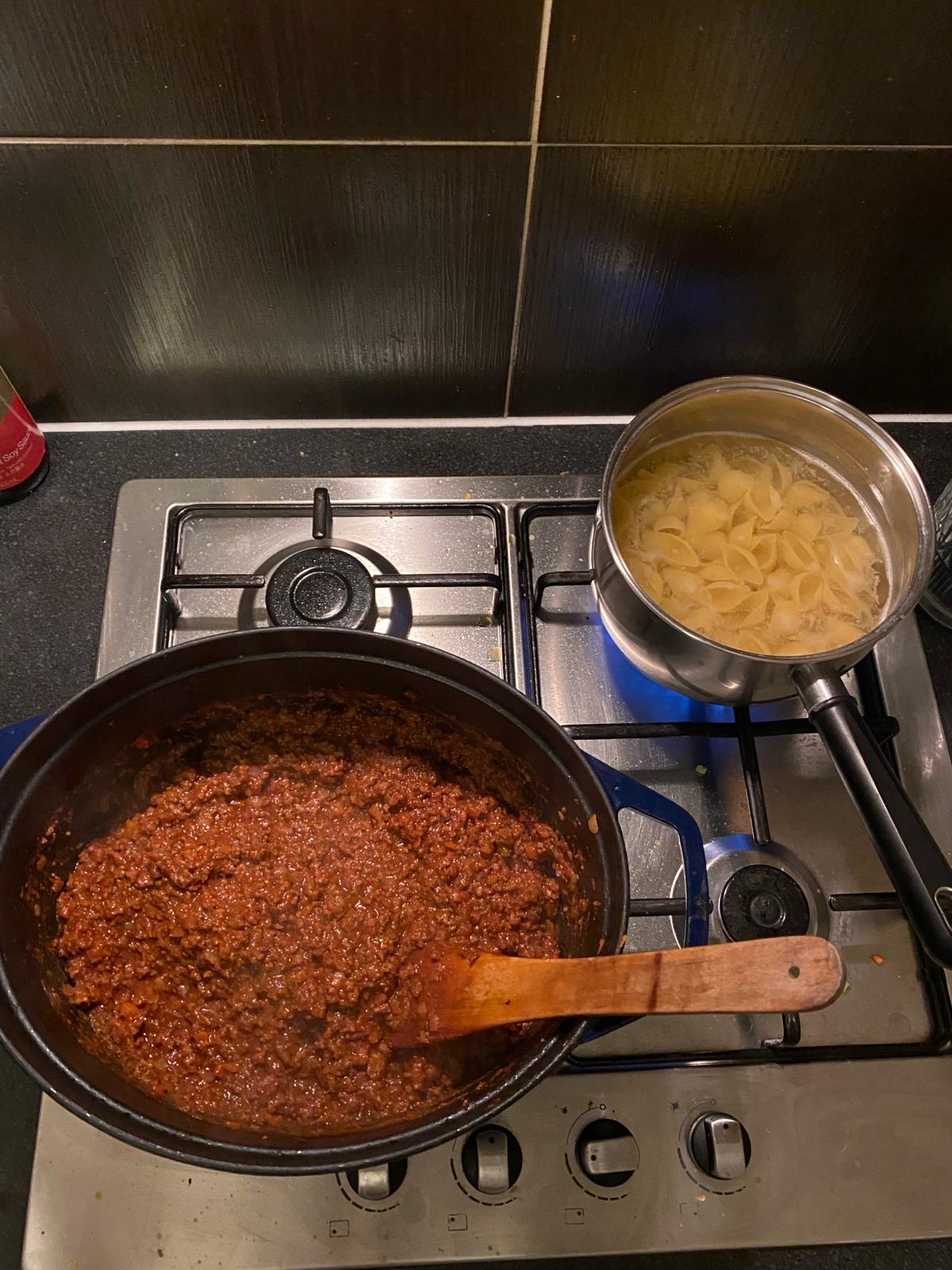 Photo of red wine being poured into a pot of bolognese.